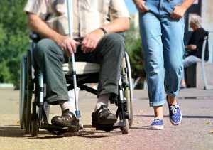 Two people moving forward, one of whom is in a wheelchair.
